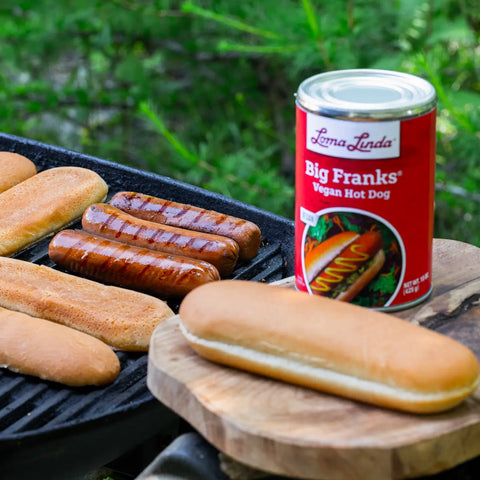 Big Franks grilling on an outdoor barbecue with buns – plant-based hot dog alternative prepared for a cookout