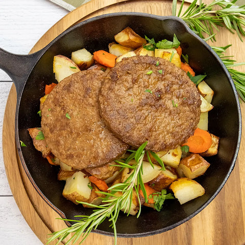 Prime Stakes served on a cast iron skillet with roasted potatoes, carrots, and rosemary