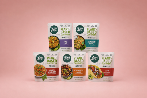Five stand-up pouches of Loma Plant-Based Goodness meal mixes arranged on a soft pink background. The packages include Pad Thai, Hawaiian Bowl, Hearty Spaghetti, Southwest Bowl, and Taco Filling.