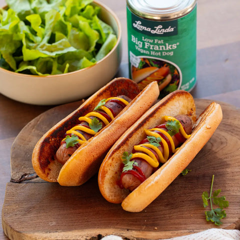 Two Low Fat Big Franks on grilled buns with mustard, ketchup, and parsley garnish – plant-based hot dog alternative served classic cookout style