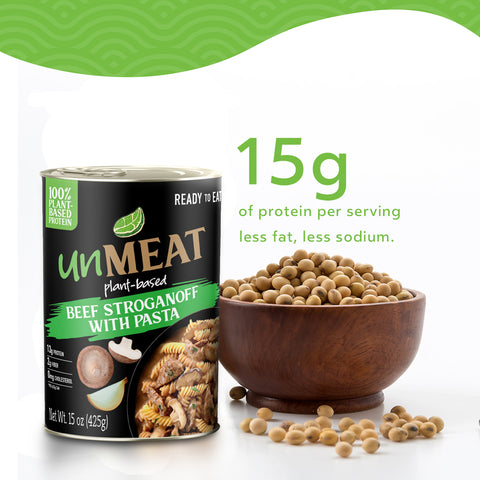 Can of 'unMEAT' plant-based beef stroganoff with pasta next to a bowl of soybeans with 15 grams of protein on a white background.