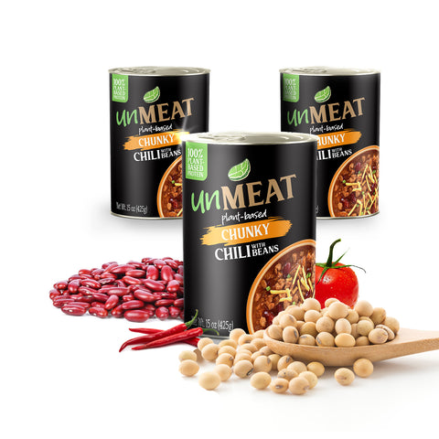 Three cans of 'UnMEAT' plant-based chunky chili with beans on a white background, surrounded by ingredients like beans and a tomato.