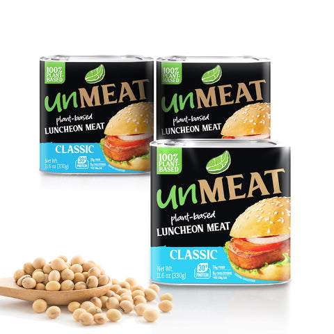 Three cans of 'unMEAT' classic plant-based luncheon meat with a scoop of beans on a white background.