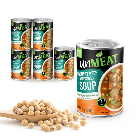 Six cans of UnMeat Country Beef Vegetable Soup with a wooden spoonful of soybeans on a white background