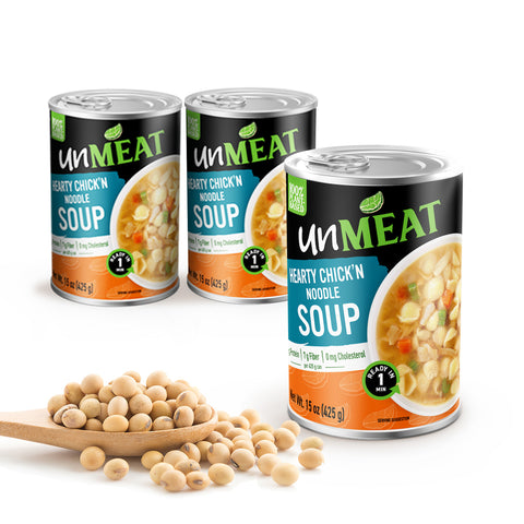 Three cans of 'unMEAT' Hearty Chicken Noodle Soup with a wooden spoonful of beans on a white background.