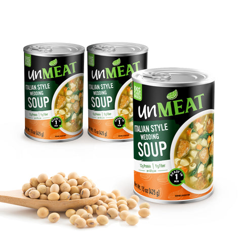 Three cans of 'unMEAT' Italian Style Wedding Soup with a wooden spoonful of beans on a white background.