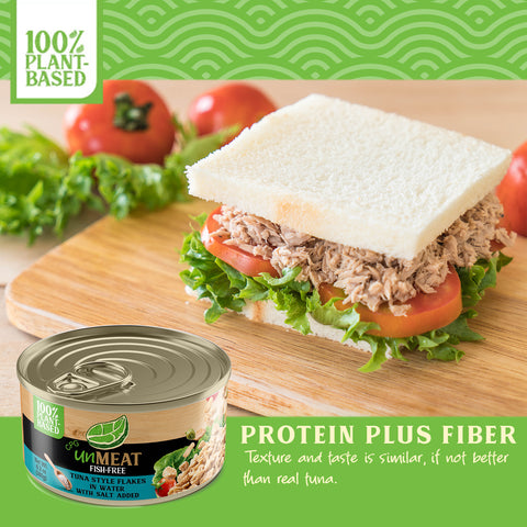 Tuna salad sandwich on a wooden board with a can of tuna and vegetables in the background.